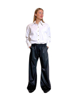 Donna che indossa pantaloni gessati antracite e vino con camicia bianca, stile contemporaneo e confortevole.