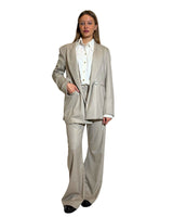 Modella che indossa un blazer doppiopetto garcon flanella gessata, posa in stile elegante con pantaloni coordinati.