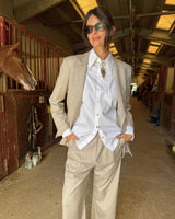 Model wearing a blazer doppiopetto garcon flanella gessata with a white shirt, standing in a barn setting.