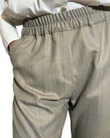 PANTALONE SABBIA LIEVEMENTE GESSATO con vita elasticizzata e linee morbide, abbinato a camicia bianca.