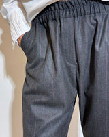 Pantaloni gessati antracite e vino con linea ampia e morbida, stile sartoriale moderno e comfort.