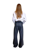 Pantaloni gessati antracite e vino visti da dietro, modello ampio e morbido con camicia bianca.