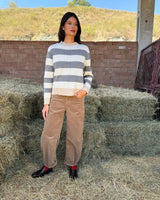 Modello che indossa PANTALONE BAGGY IN VELLUTO COGNAC con maglione a righe in un ambiente rustico.
