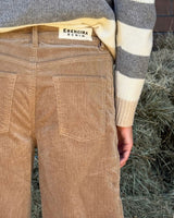 PANTALONE BAGGY IN VELLUTO COGNAC worn by model with striped sweater and ERENDIRA DENIM tag.