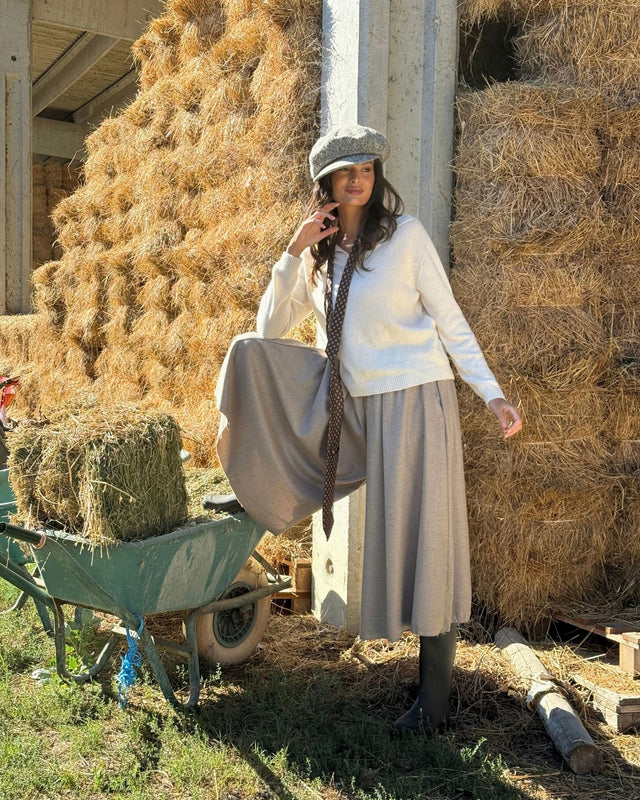 Modella che indossa la GONNA PANTALONE IN FLANELLA SABBIA, ambientata in un campo con balle di fieno.