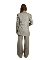 Back view of a woman wearing a light grey blazer doppiopetto garcon flanella gessata with matching pants.